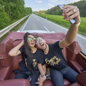 A couple in a convertible takes a selfie on a sunny road trip