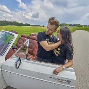 Couple embracing by a convertible car on a tranquil country road