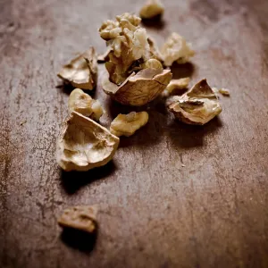 Cracked walnut shells and pieces scattered on a rustic wooden surface