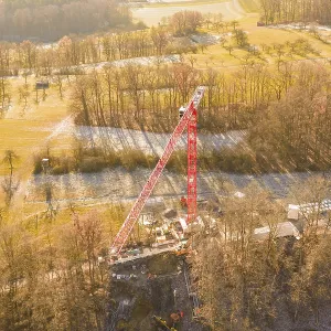 Crane dominates construction site in autumn landscape Crane dominates construction site in autumn landscape
