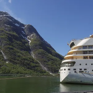 A cruise ship against a majestic mountain backdrop with a clear blue sky A cruise ship against a majestic mountain backdrop with a clear blue sky