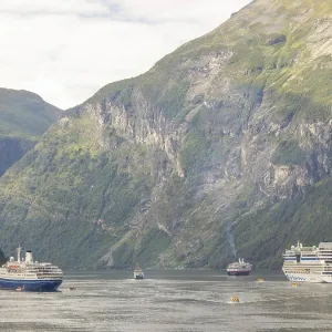 Cruise ships sail through a fjord in front of impressive mountains