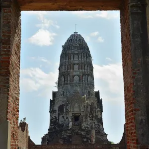 Crumbling brick walls frame a majestic ancient prang under a partly cloudy sky Crumbling brick walls frame a majestic ancient prang under a partly cloudy sky