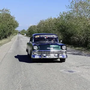 Cuba, Cuba, Central America, Green vintage car travelling on a rural road Cuba, Cuba, Central America, Green vintage car travelling on a rural road