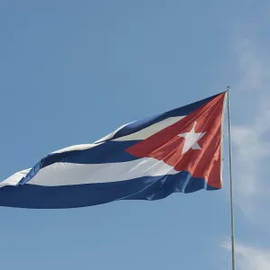 Cuba flag against blue sky and sunshine Cuba flag in front of blue sky and sunshine
