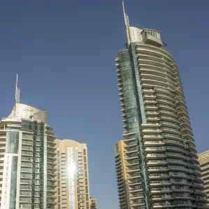 Two curved, glass skyscrapers stretch across a modern cityscape