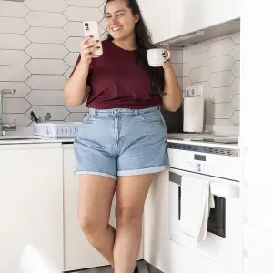 A curvy woman in casual clothes stands in a bright kitchen