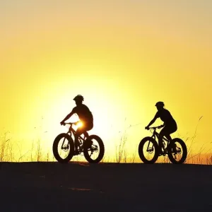 Three cyclists on fatbikes backlit at sunset