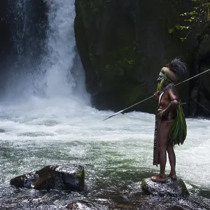 Decorated and painted tribal chief standing in front of a waterfall in the Highlands Decorated and painted tribal chief standing in front of a waterfall in the Highlands