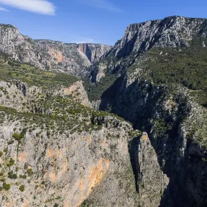 Deep gorge with imposing rocks and green vegetation under a clear blue sky