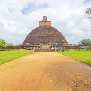 Dirt road leading to centered Jetavanaramaya Dagoba or stupa ruins on a beautiful blue sky day in ancient capitol of