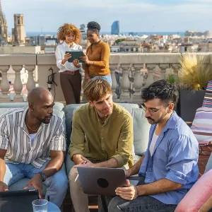 Diverse colleagues collaborate on a rooftop terrace in barcelona during a break