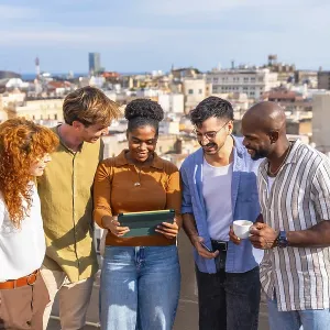 Diverse colleagues networking and smiling on a sunny barcelona rooftop during a casual work break