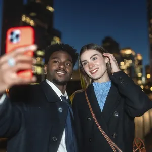 Diverse couple happily capturing a moment together using a mobile device for a selfie Diverse couple happily capturing a moment together using a mobile device for a selfie