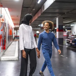 Diverse young couple walking hand in hand through an underground parking garage