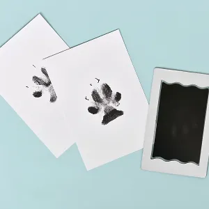 Dog paw prints on white paper next to ink pad on blue background
