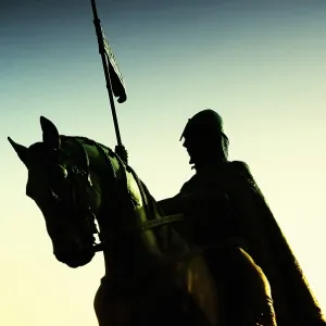 Dramatic silhouette of a st. Venceslav knight on horseback with a spear and flag at sunset