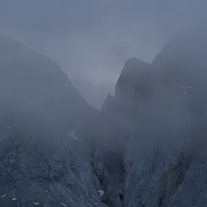 Una vista dramática de los Alpes bávaros envueltos en una espesa niebla durante el atardecer Una vista dramática de los Alpes bávaros envueltos en una espesa niebla durante el atardecer