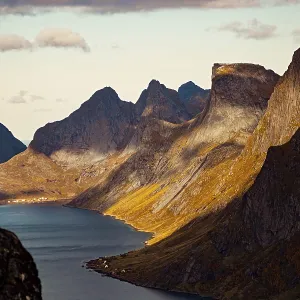 Dramatic view of a fjord with towering mountains casting shadows along the landscape Dramatic view of a fjord with towering mountains casting shadows along the landscape