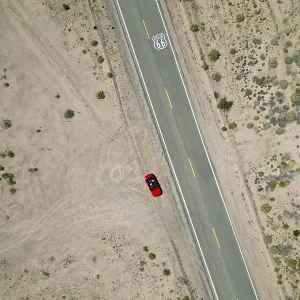 Drone shot of Route 66 with Route 66 sign on the road and red Ford Mustang convertible Drone shot of Route 66 with Route 66 sign on the road and red Ford Mustang convertible