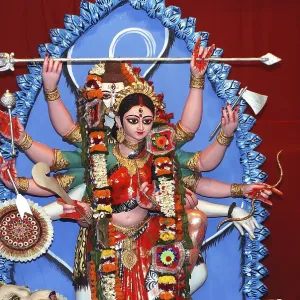 Durga clay model holding weapons and god shiva in background on Durga puja