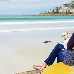 Elderly woman sitting by a beach with a dog on her lap Elderly woman sitting by a beach with a dog on her lap