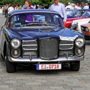 Elegant black coupe at a classic car show surrounded by other classic vehicles