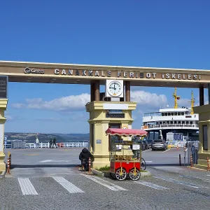 The entrance to the ferry terminal with clock and a kiosk in sunny weather
