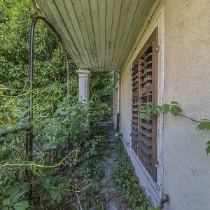 Entrance to the overgrown garden of a multi-storey residential building built in 1903 in front of demolition work
