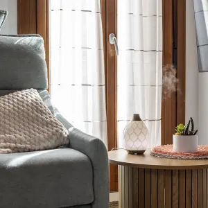 Essential oil diffuser releasing aromatic mist on a side table creating a relaxing atmosphere in a modern home