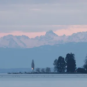 Evening light turns the sky pink over a peaceful lake with mountains Evening light turns the sky pink over a peaceful lake with mountains