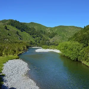 Extensive river course through green mountains under a clear sky