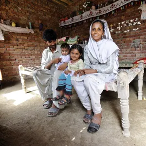 Family sitting in a new house made of bricks that they received from a relief organisation