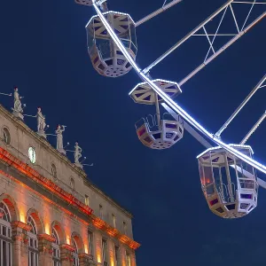 Ferris wheel cabins rotating over bayonne city hall illuminated in orange during christmas night in france Ferris wheel cabins rotating over bayonne city hall illuminated in orange during christmas night in france