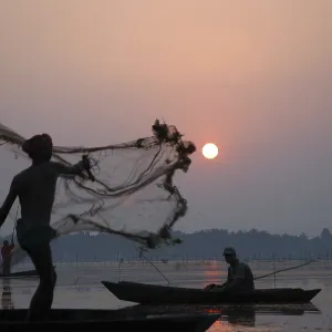Fisherman in boat throwing net in silhouette