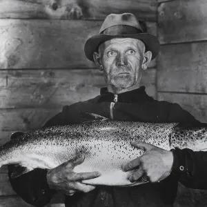 Fisherman with large salmon, presumably a king salmon or quinnat (Oncorhynchus tshawytscha)