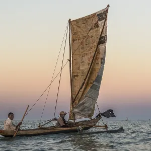 Fishermen at sunrise in traditional Pirogue outrigger boat on the Indian Ocean