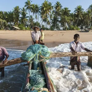 Fishermen at work, fishermen pushing fishing boat from sandy beach into the sea Fishermen at work, fishermen pushing fishing boat from sandy beach into the sea