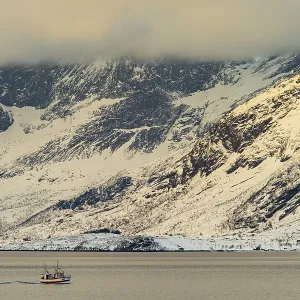 Fishing boat in winter Scandinavian landscape at the fjord