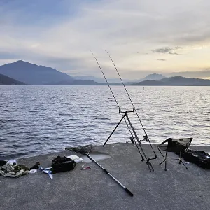 Two fishing rods on a tripod with many accessories set up on Lake Zug