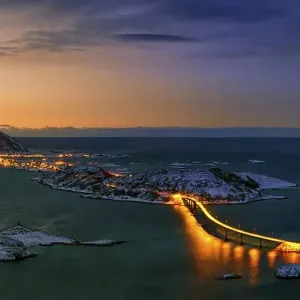 Fjord with an illuminated bridge in winter at sunset