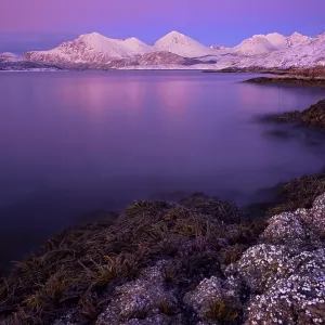 Fjord with stones in front of a mountain range in the evening light Fjord with stones in front of a mountain range in the evening light