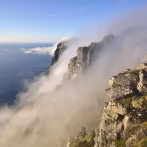 Fog falls down a steep cliff to the sea Fog falls down a steep cliff to the sea