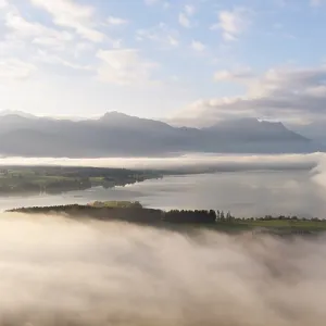 Foggy landscape with view of Lake Forggensee and mountain skyline in the background