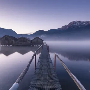 A footbridge leads to three huts in fog