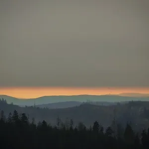 Forest and mountains at dusk below a cloudy horizon Forest and mountains at dusk below a cloudy horizon