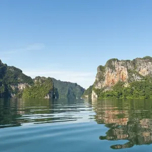 Forested karst limestone mountains reflected in the water