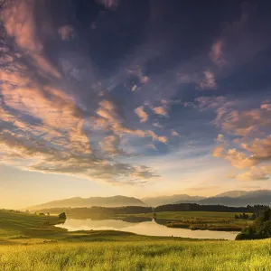 Forggensee with mountain meadow and the Allgaeuer mountains in the background at sunrise Forggensee with mountain meadow and the Allgaeuer mountains in the background at sunrise