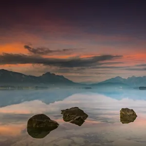 Forggensee with reflection of the cloudy sky and the Allgaeuer mountains in the background at sunrise Forggensee with reflection of the cloudy sky and the Allgaeuer mountains in the background at sunrise
