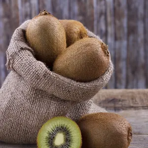 Fresh kiwi in burlap sack on old rustic wooden table Fresh kiwi in burlap sack on old rustic wooden table